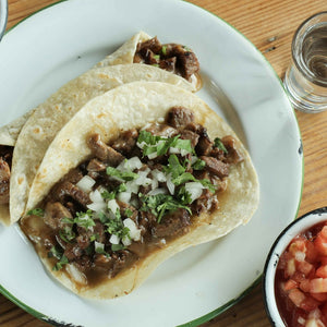 A taco filled with Sirloin Steak with onion and parsley and a side of Pico de Gallo using Unbleached Flour Tortilla