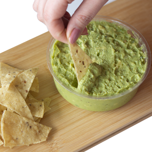A hand dipping nacho chips in Chunky Guacamole with a side of corn nacho chips